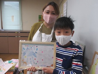 古賀先生と作品を持った男の子の画像
