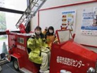 子ども達が消防士の服を着て消防車の搭乗している様子