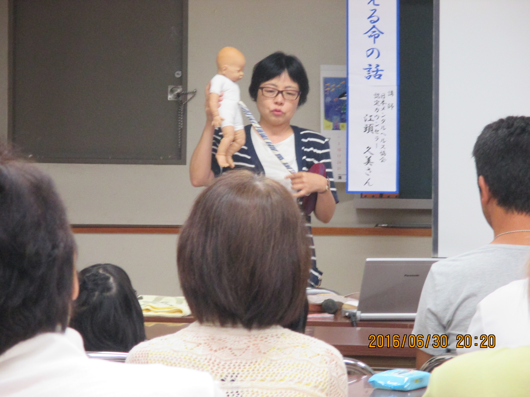 赤ちゃん人形をもって話す講師の写真