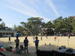 スピーカーを背に校庭で遊ぶ子どもたちの写真