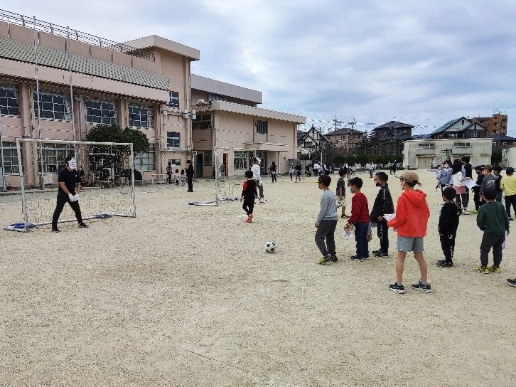 サッカーのゴールを守る鬼に挑戦する子ども達の写真