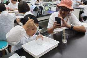 参加者の子どもが、スライムを混ぜたり伸ばしたりしながら感触の変化を楽しんでいる様子