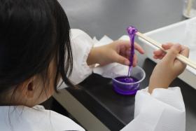 参加者の子どもが、完成したスライムを手で伸ばしたり触ったりしながら感触を確かめている様子
