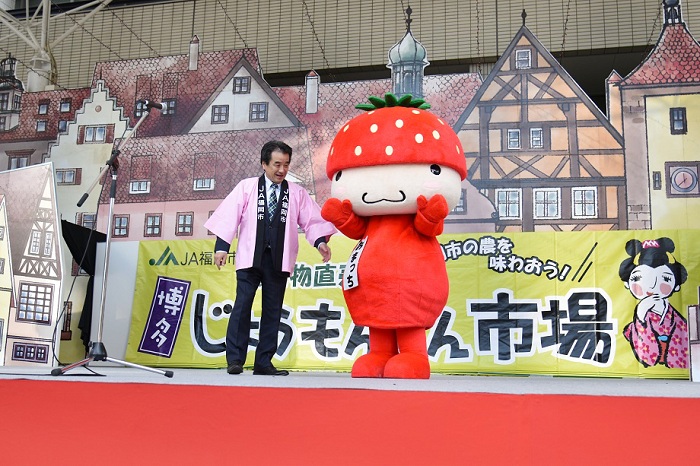 「あまおう」をモチーフにしたキャラクターが、イベントのステージで挨拶している写真