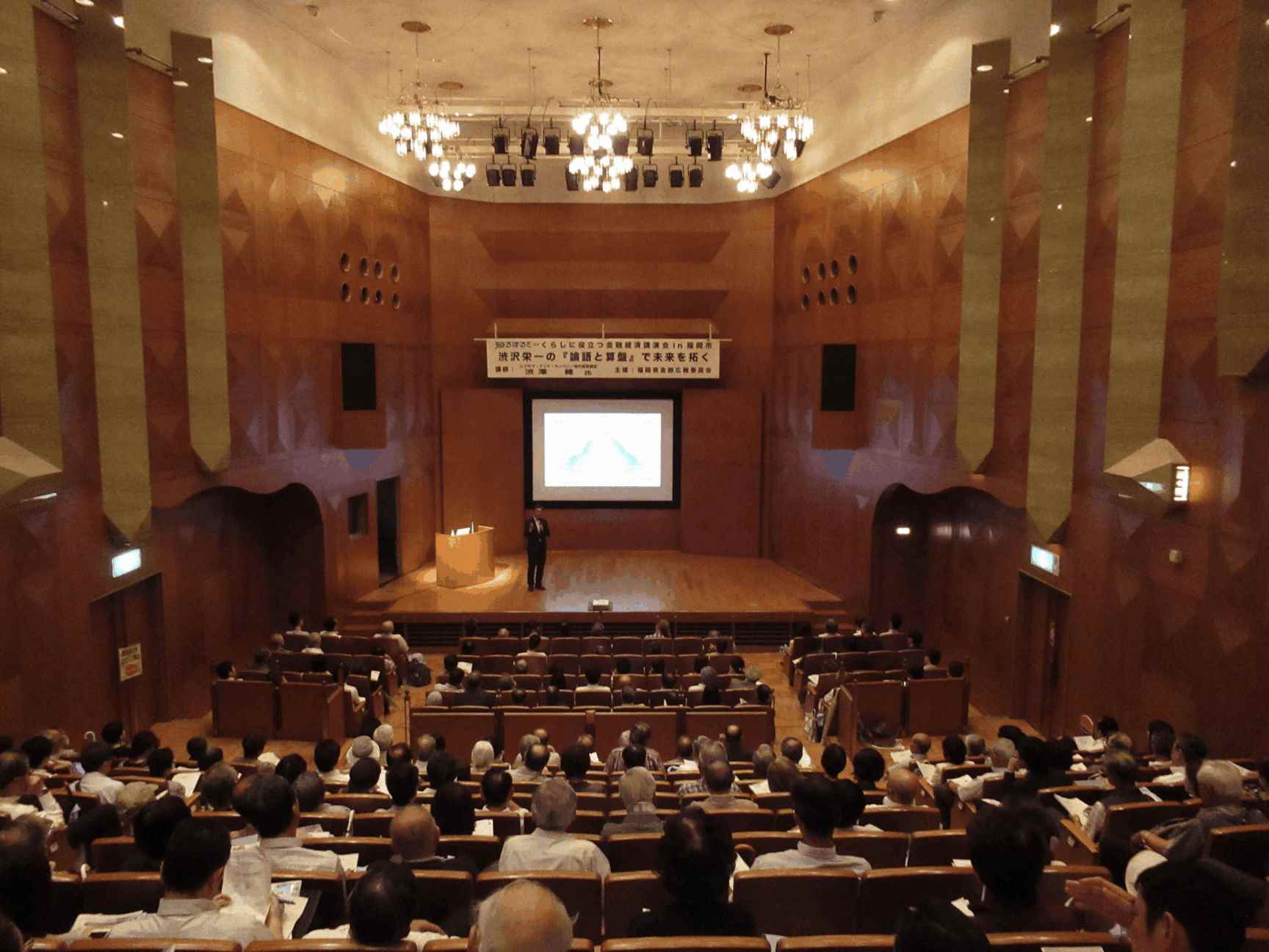 画像：金融広報委員会講座の様子。ホールの後方からの写真。