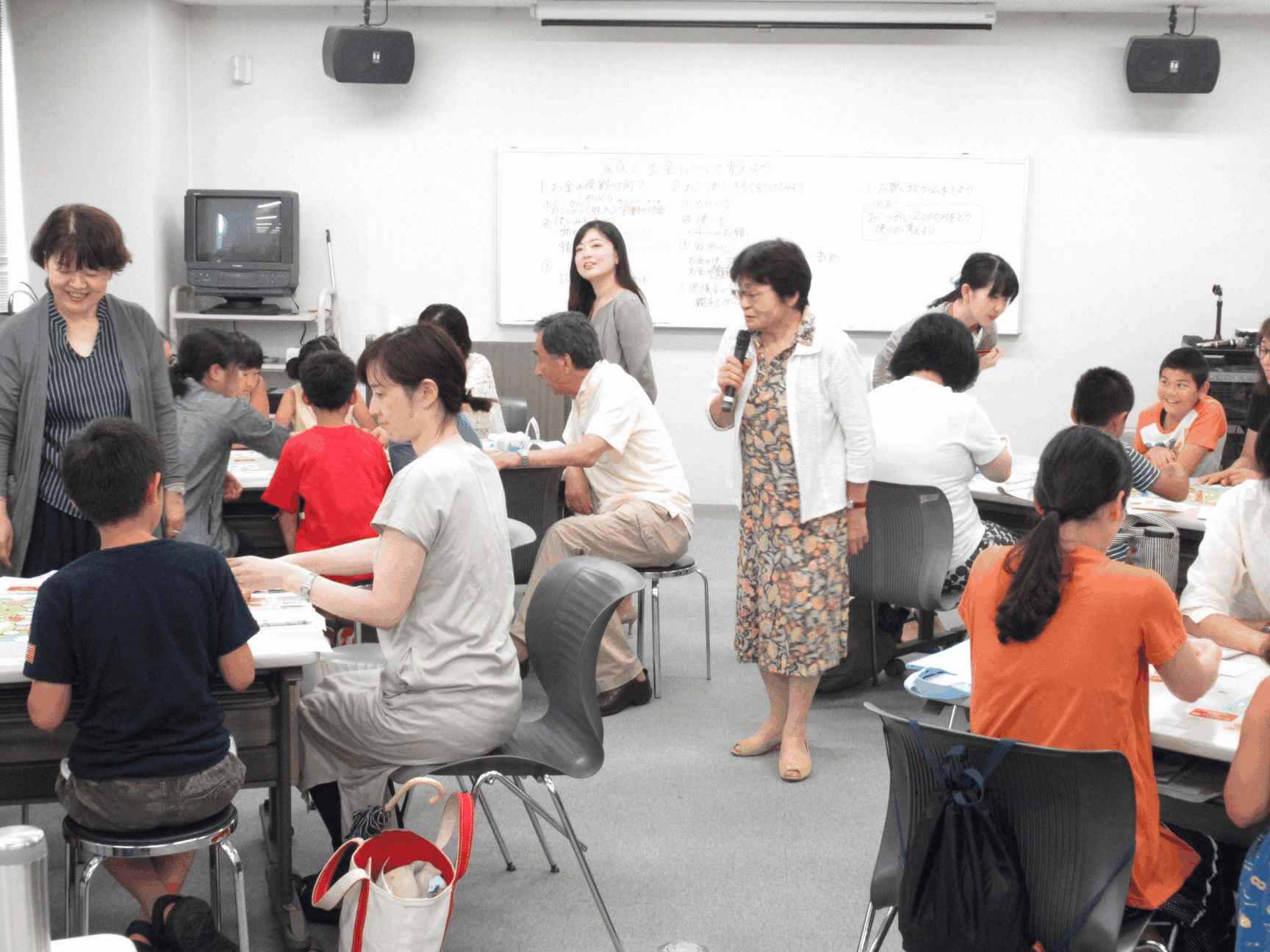 画像：お金の講座受講者に講師がおこずかいゲームの説明をしている様子