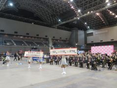 ファイ太くん広場で演奏に合わせてクイズを出題する福岡市消防カラーガード隊の写真