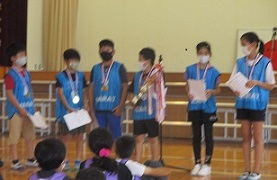 トロフィーとメダルを持つ優勝チームのメンバーの画像