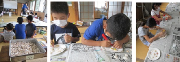 子どもたちが大小さまざまな貝やサンゴなどを使って紙皿工作する写真