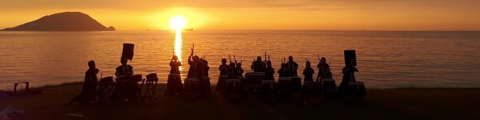 画像：勝馬の夕日を背に演奏する金印太鼓