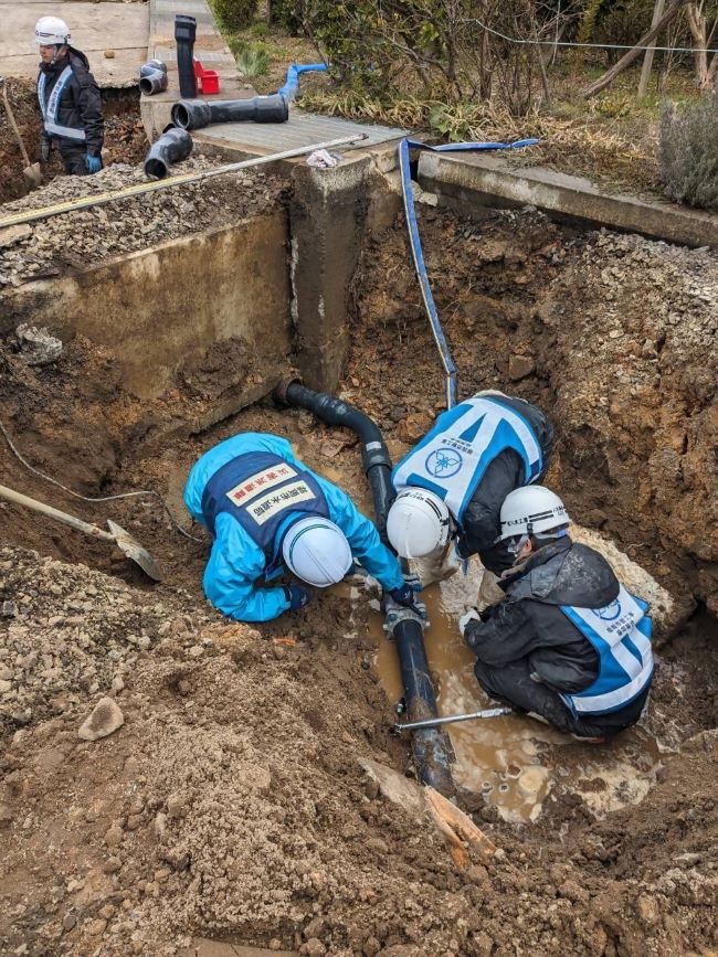 復旧隊員が掘った地面に降りて、漏水した水道管の状態を確認する様子