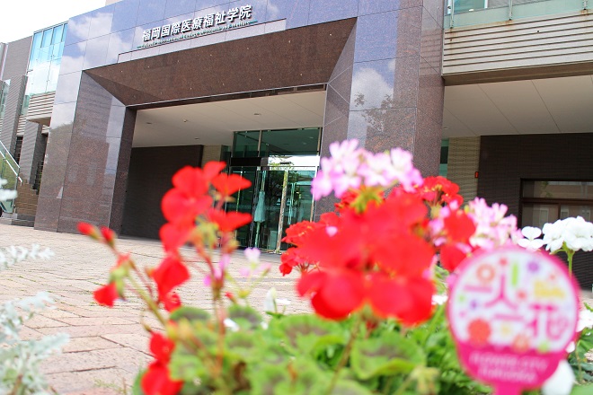 福岡国際医療福祉学院の正面玄関と赤い花が写った写真
