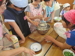 上級生が下級生に料理を教えている写真