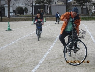 自転車に乗って競争する子どもと大人の様子