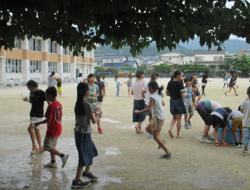 校庭で子どもたちが水遊びしている様子