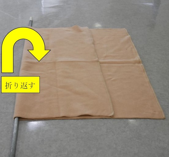 ３　毛布の上に置いた棒を中心に毛布を２つに折る。