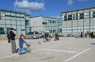 自転車に乗った子どもが、踏切り前の停止線で一旦停止、耳を澄まし、左右確認する写真