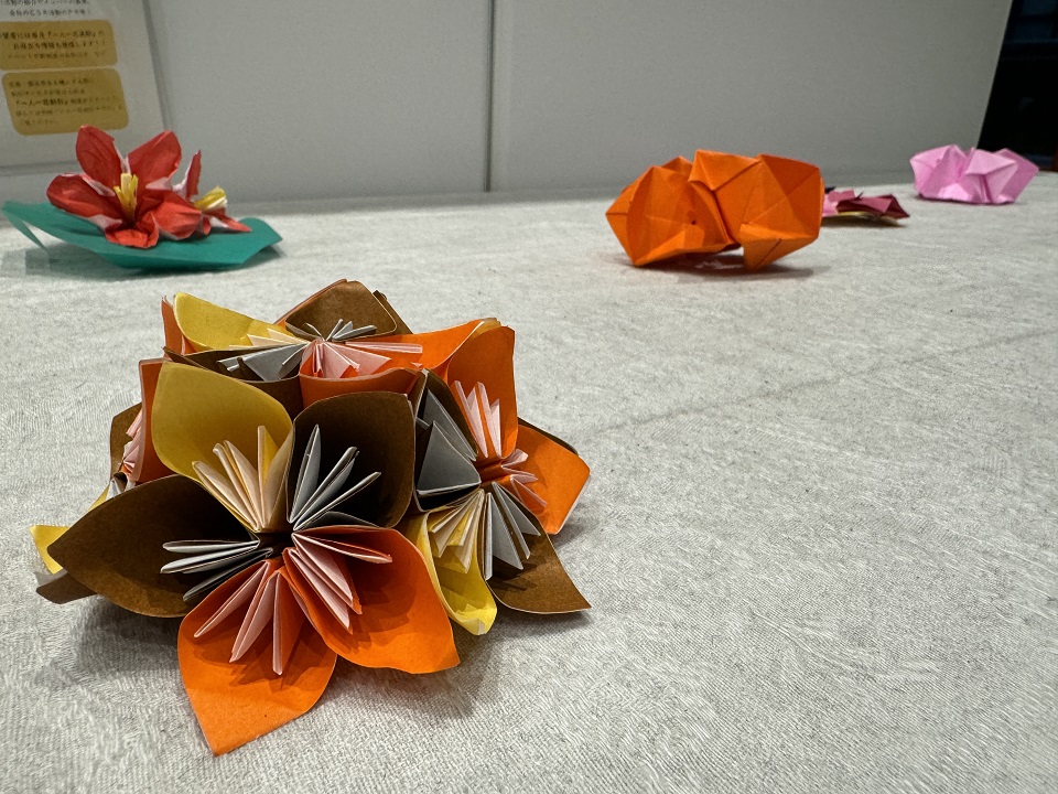 黄色、茶色、オレンジ色の折り紙で作られた花の写真