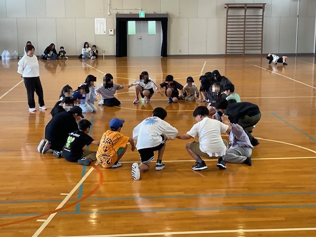 輪になって隣の人と指一本で割りばしを支え経ったり座ったり