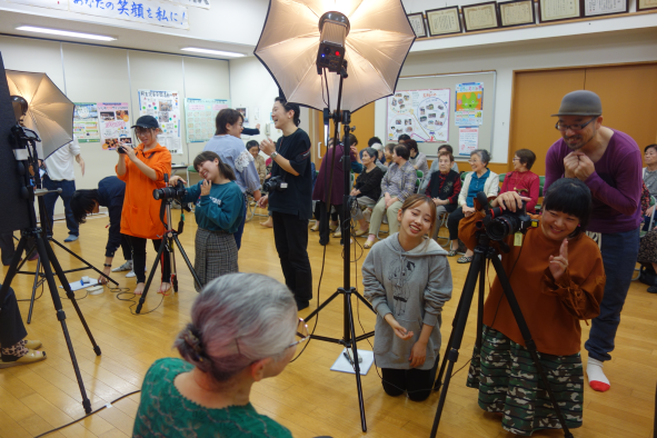専門学生が照明やレンズを調節しながら、参加者の記念写真を撮影している写真