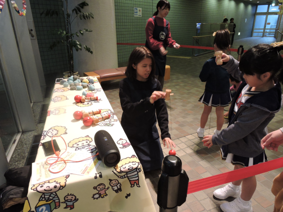 子どもが学生にけん玉を教わっている写真