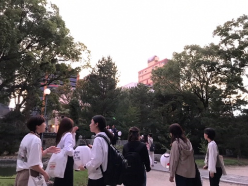 生徒が提灯を片手に通りで外国語で案内している写真
