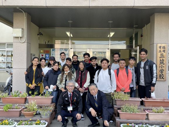 三筑小学校玄関前で留学生と教師が写っている集合写真