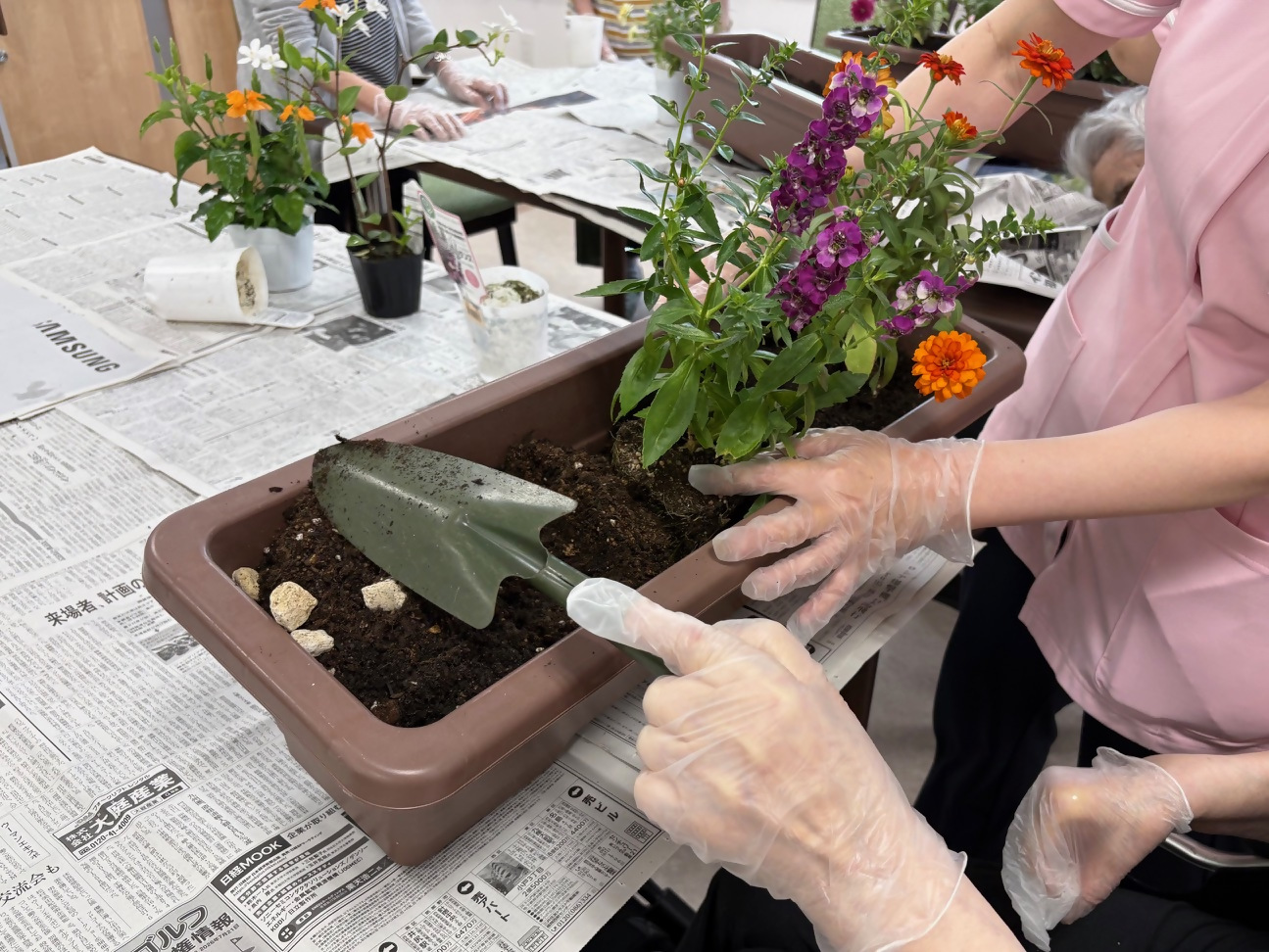植物を植える職員と入居者の写真