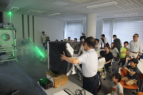 講師がレーザーを用いて空気砲の断面を観察する実験を行っている様子