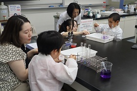 参加者が、お酢や重曹、クエン酸などの身近な材料を加え、液体の色の変化を楽しんでいる様子