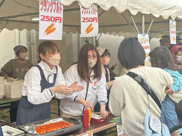 フランクフルトの販売を手伝う区長（写真左）