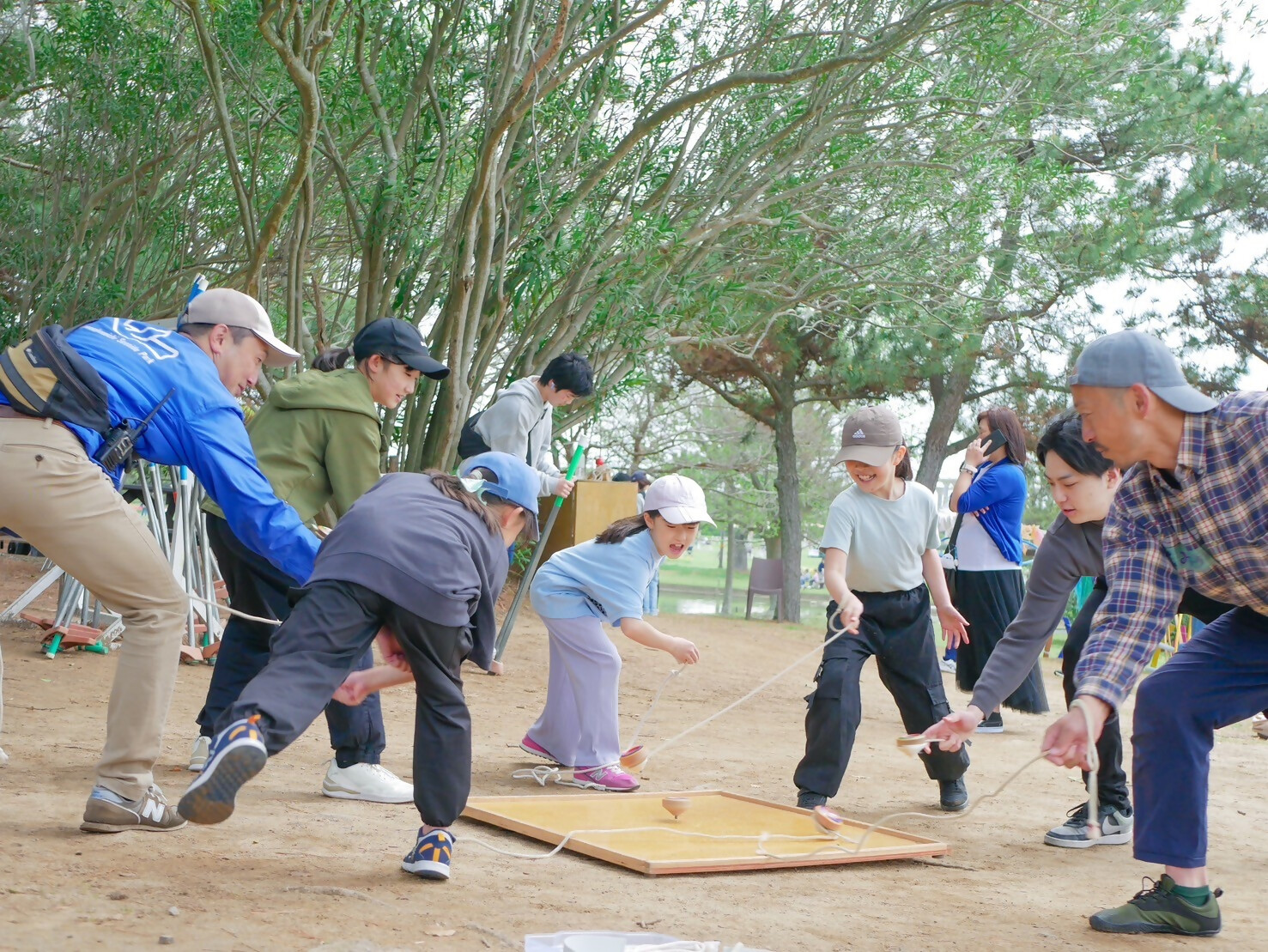 あそびばサポーターよと、駒回しを楽しむ子どもと保護者