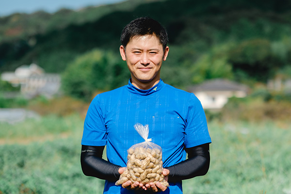 写真：にこっと落花生の商品を手に持つ吉積元樹さん