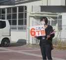6丁目のボードを手に、子どもたちに集合をかけている６丁目子ども会育成委員の写真