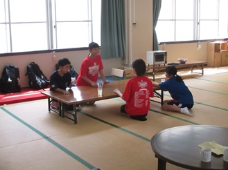 畳の上の長机に集まってくつろぐ子どもたちの写真