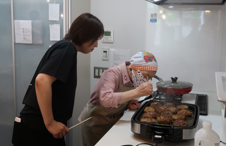 施設スタッフのサポートを受けながらハンバーグの確認をする平川さん