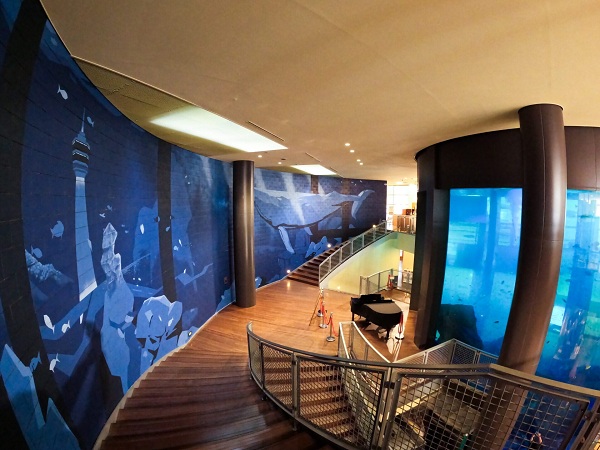 ベイサイドの水槽の手前に置いてあるストリートピアノの写真