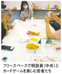 フリースペースで相談員（中央）とカードゲームを楽しむ若者たち