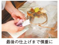飾り付けリースを最後の仕上げまで慎重に製作している写真