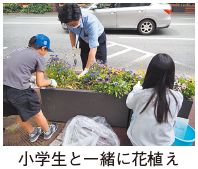 小学生と一緒に花植えをしている写真