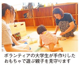 ボランティアの大学生が手作りしたおもちゃで遊ぶ親子を見守る写真