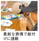 博多人形の絵付けの写真(真剣な表情で絵付けに挑戦)