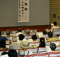 写真:講演会に参加する聴講者の皆さんの後ろ姿 配布資料に熱心に目を通している