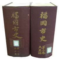 写真：旧『福岡市史』の1巻2巻を並べて背表紙を写したもの。A5判、海老茶色のクロス貼り、題字は金の箔押し。2冊とも1000頁を超す分厚い書籍である。