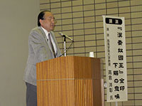 写真：講堂の檀上に立ち、演台で講演される高倉洋彰先生