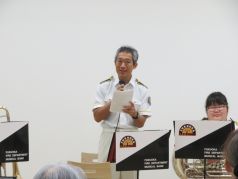 曲の合間で司会をする福岡市消防音楽隊の写真