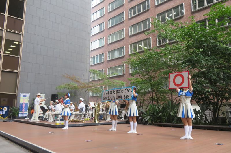 ふくぎん本店広場でパネルを使いクイズを出題する福岡市消防カラーガード隊の写真