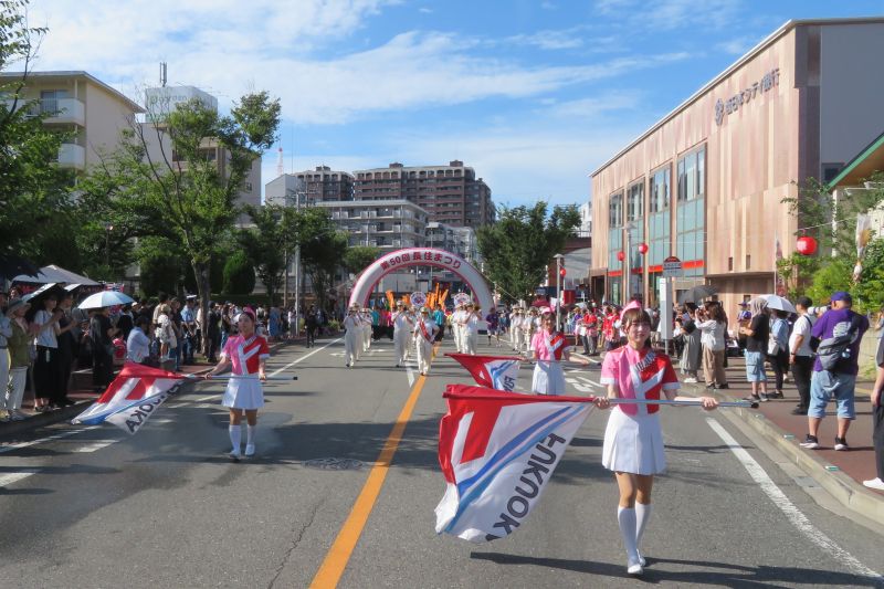 長住大通りでパレードをする福岡市消防音楽隊カラーガード隊の写真
