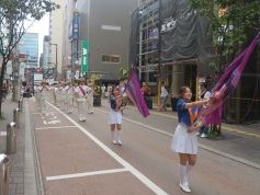 中洲大通りでパレードをする福岡市消防音楽隊カラーガード隊の写真