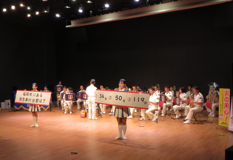 演奏と一緒にクイズを出題する消防音楽隊の写真
